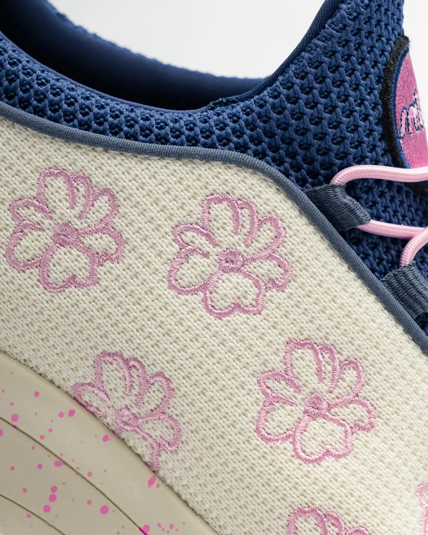 Close-up of the Snibbs Orbit - Anna The Nurse sneaker with a knit upper, cream panel, pink flowers, navy mesh, and pink laces.