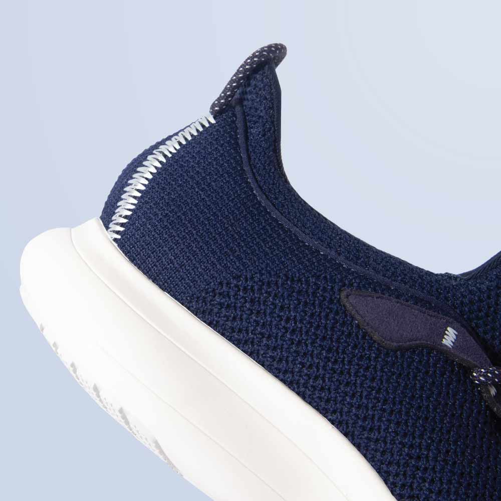 Close-up of the Snibbs Orbit in Maritime Blue, featuring a breathable knit upper and slip-resistant sole against a light blue background.
