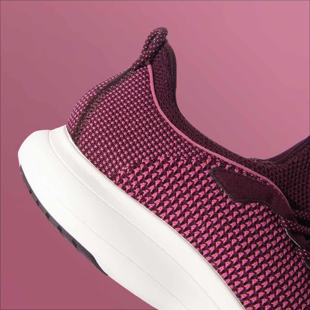 Close-up of the heel and side of Snibbs Orbit - Wine Tasting athletic shoe with a knit upper, shown against a pink background.