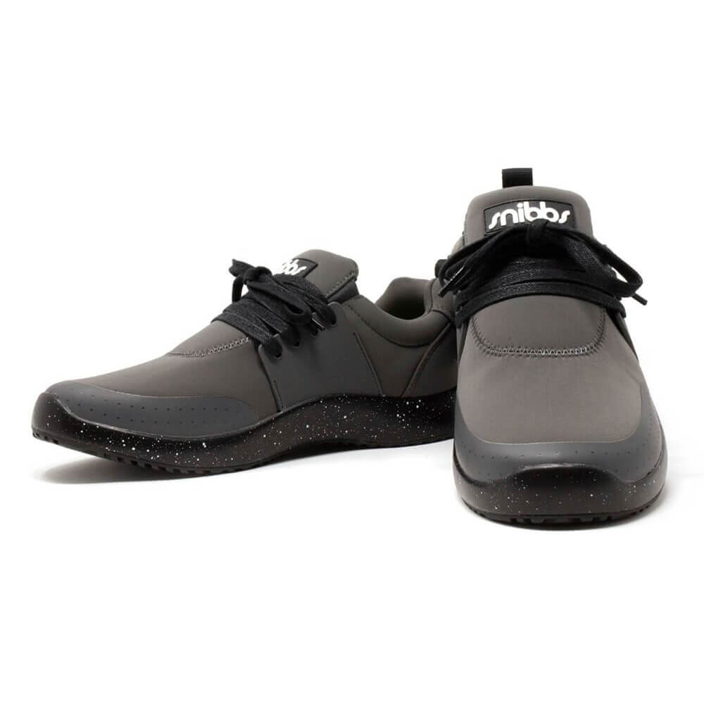 A pair of charcoal work sneakers in sleek gray and black, featuring black laces and speckled black soles. Designed for all-day comfort, these slip-resistant shoes display the Snibbs logo on the tongue. One shoe is shown facing forward while the other is a