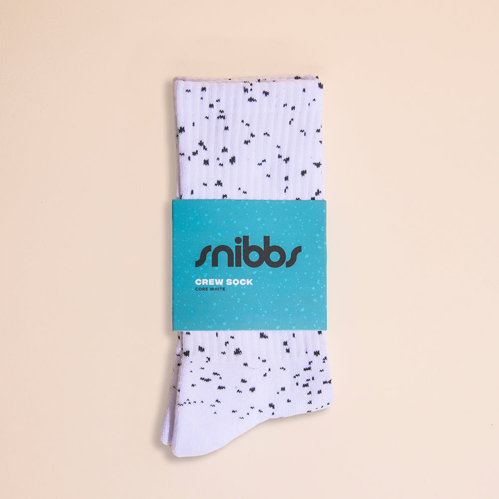 A pair of Snibbs Crew Socks - Core White, padded and structured, is folded in blue packaging on a beige background.
