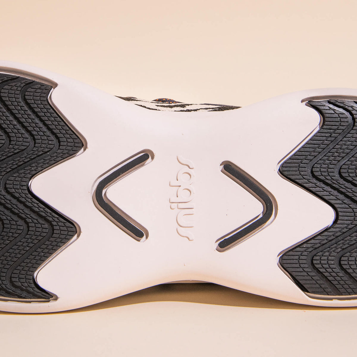 Close-up of the sole of the Snibbs Orbit - Snow Leopard shoe, featuring black textured rubber grip patterns, a white midsection, and “snibbs” embossed in the center. This slip-resistant sole pairs with a breathable knit upper and lightweight construction 