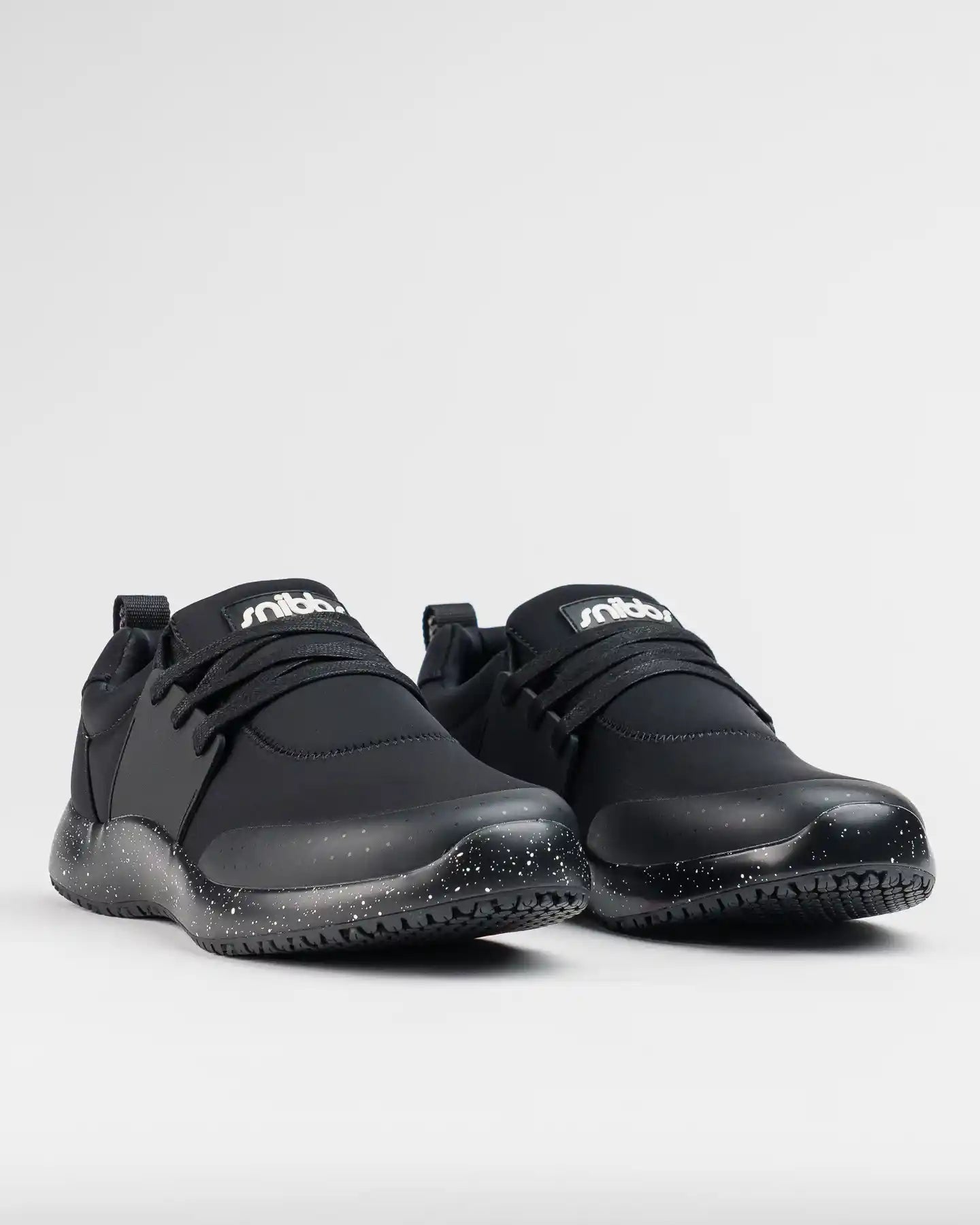 Snibbs Spacecloud 2.0 - Black Speckle: Vegan black athletic shoes with black laces, slip-resistant speckled white soles, on light background.