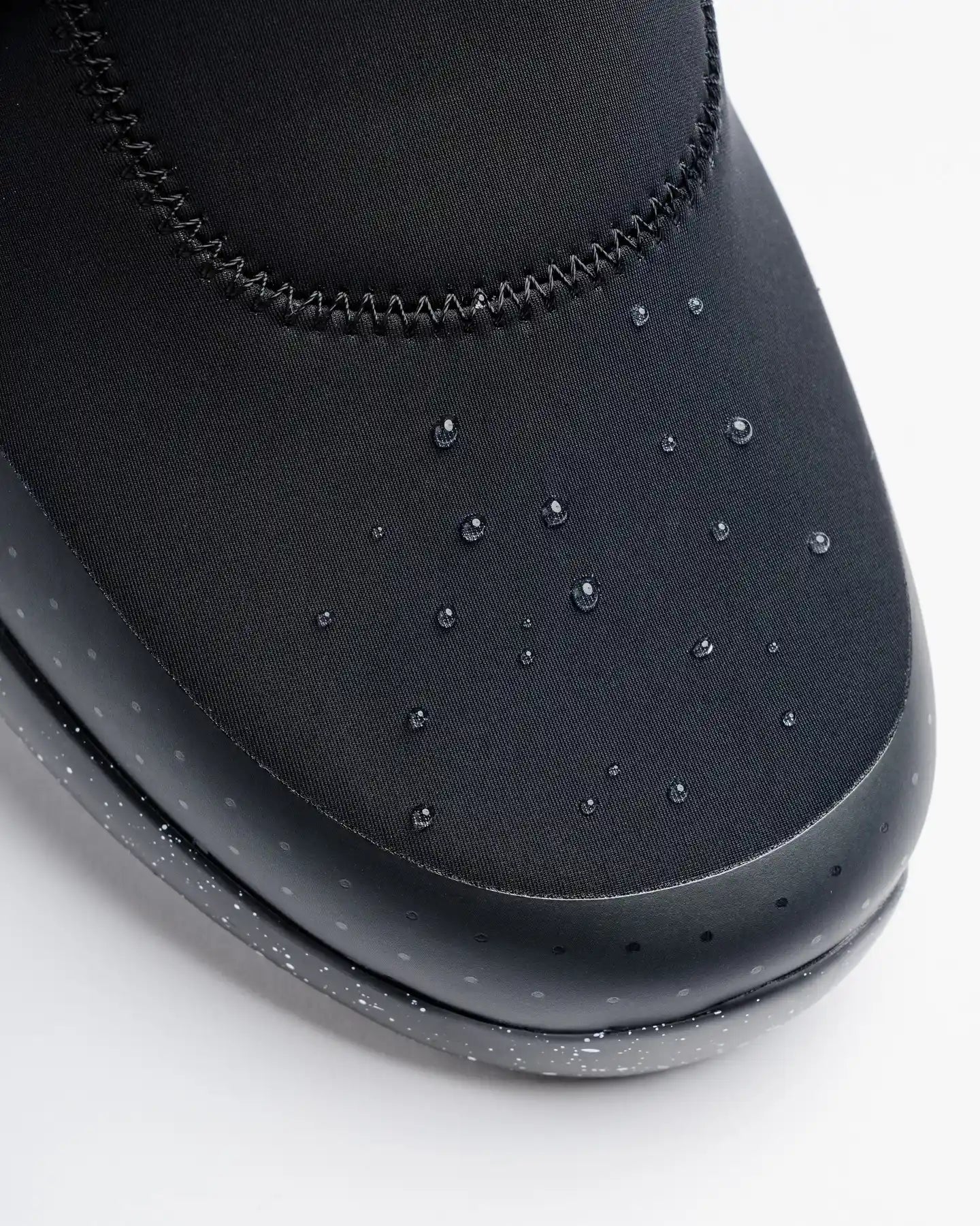 Close-up of Snibbs Spacecloud 2.0 - Black Speckle sneaker with water droplets, showing its vegan, water- and slip-resistant features.