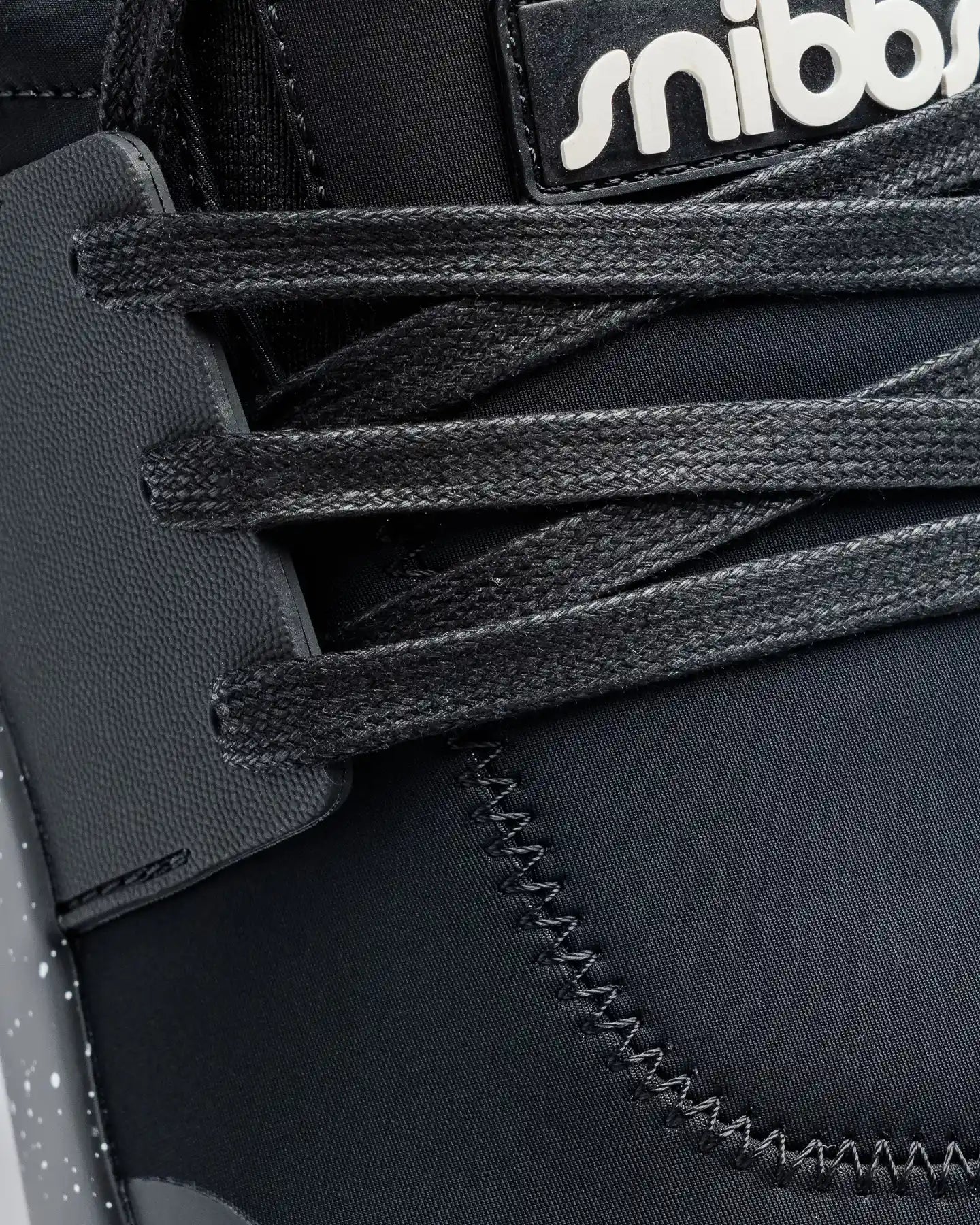 Close-up of Snibbs Spacecloud 2.0 - Black Speckle vegan work sneaker with black laces, stitching, and partial logo on the upper.