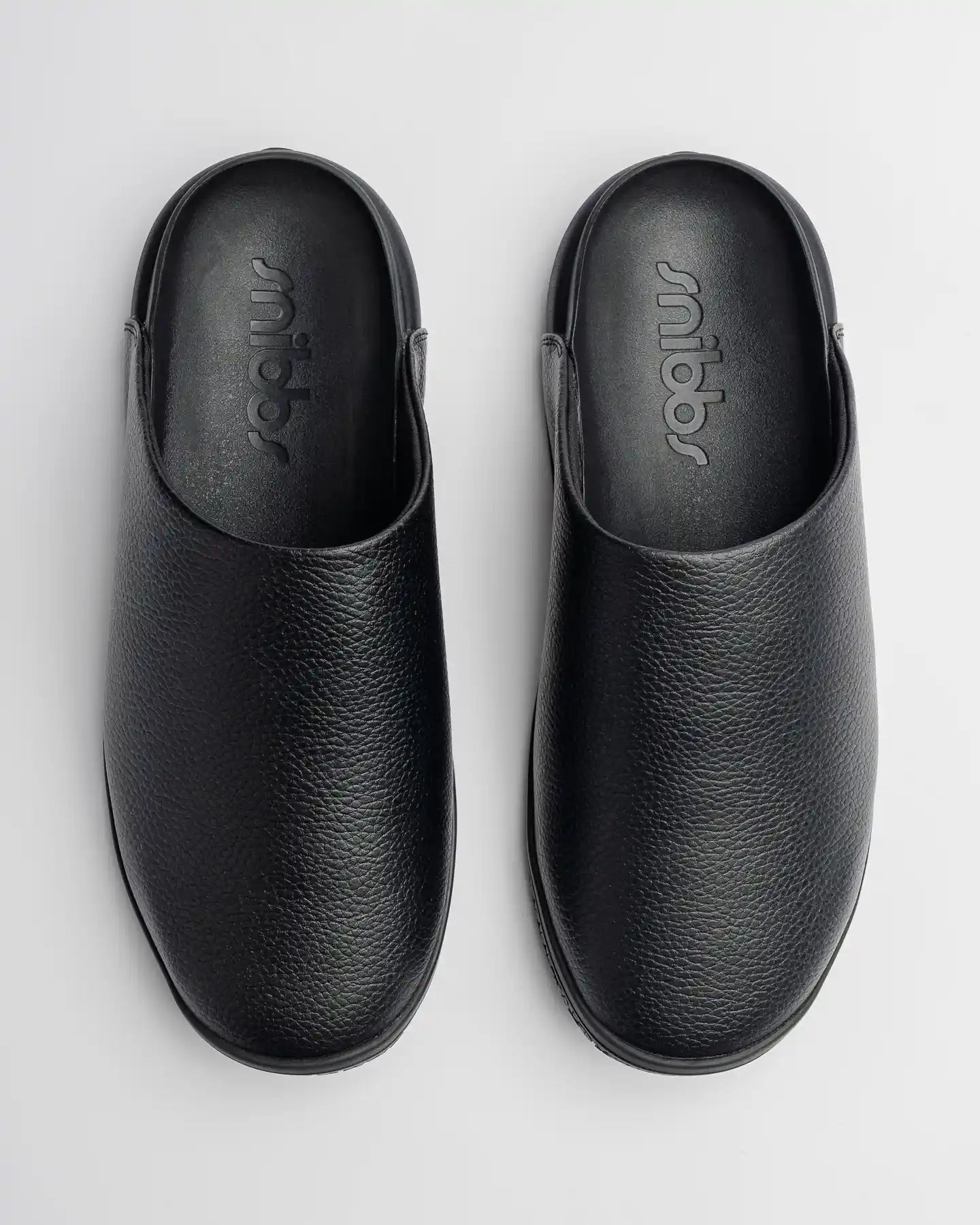 The Clog - Eclipse Black by Snibbs: black, water-resistant textured clogs shown from above on a plain light background.