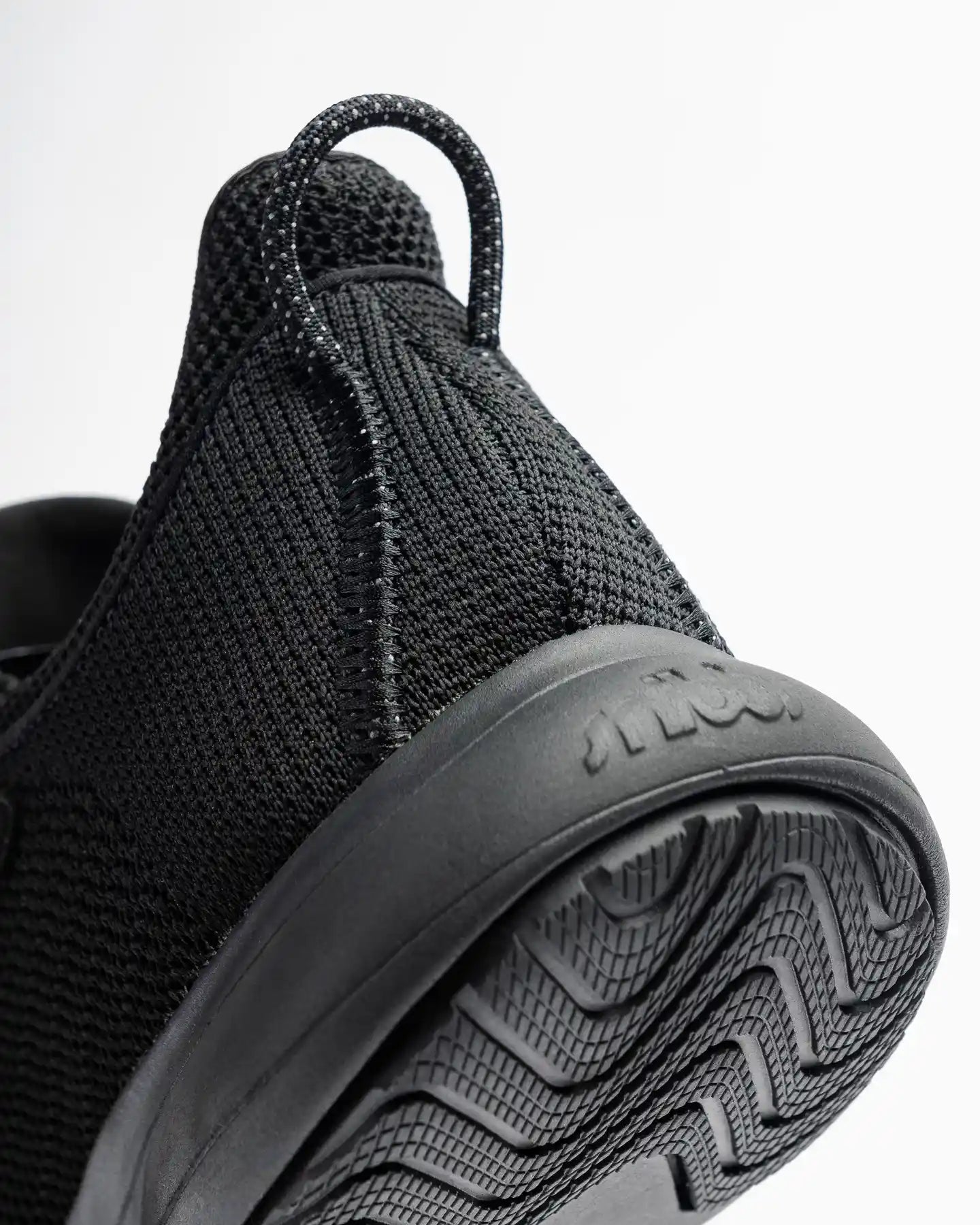Close-up of the Snibbs Orbit - Eclipse Black heel and sole, showing slip-resistant tread and breathable knit upper on white background.