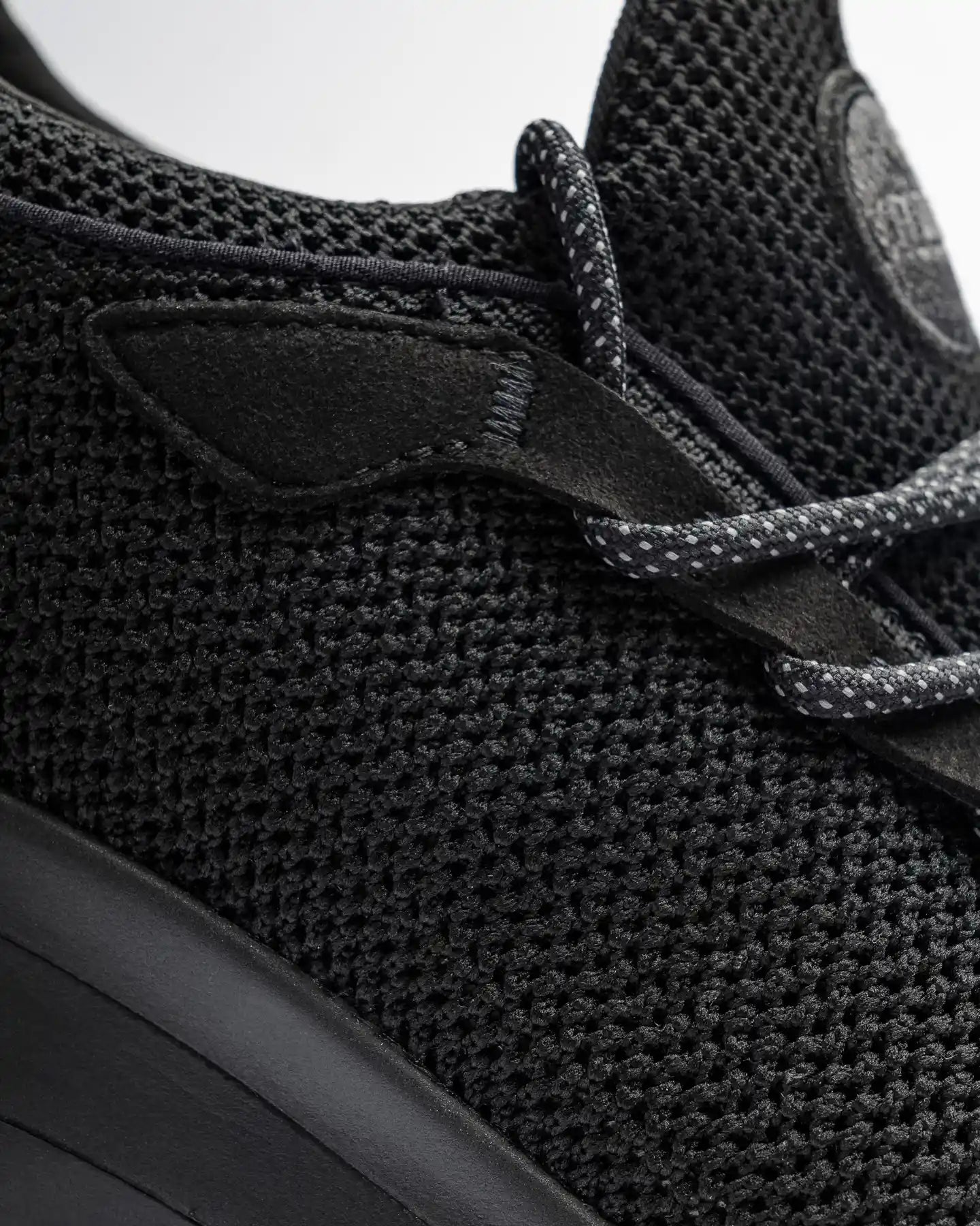 Close-up of Snibbs Orbit - Eclipse Black: breathable knit upper, round laces, slip-resistant rubber sole.