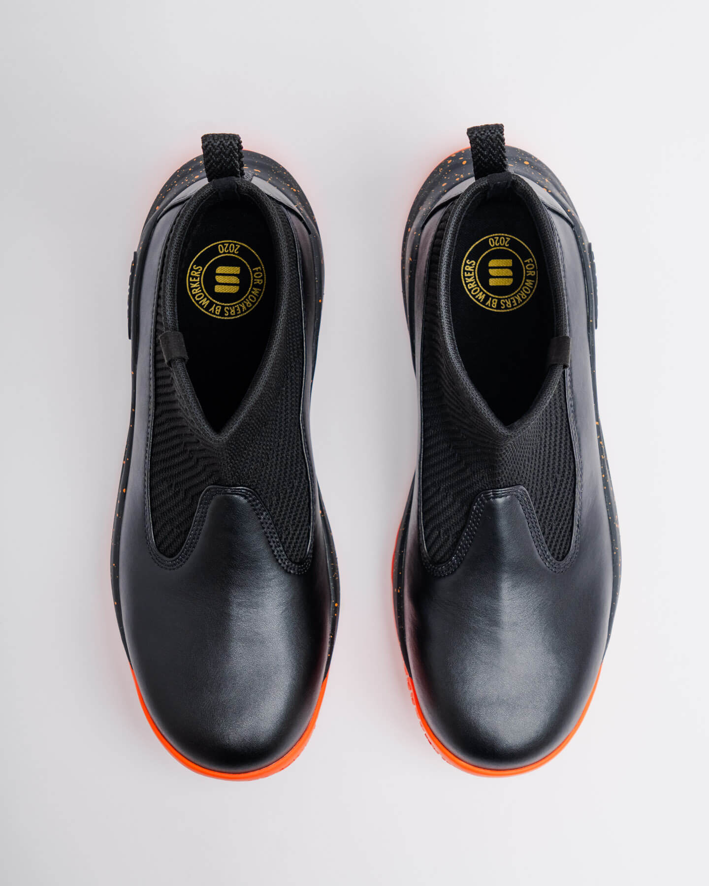 Snibbs Pro - Tangerine: black slip-on shoes with max cushioning, orange soles, top view on white background.
