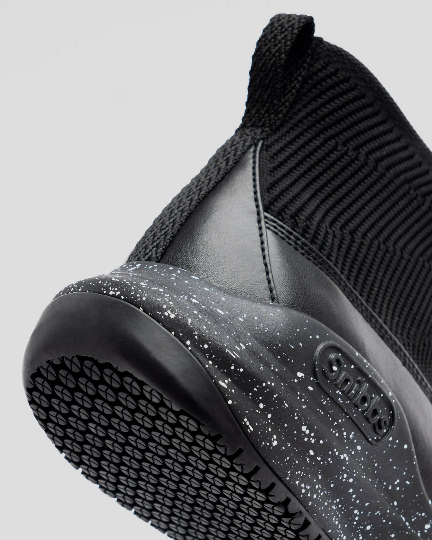 Close-up of Snibbs Pro - Black Speckle shoe with non-slip sole, speckled midsole, pull tab, and side logo.