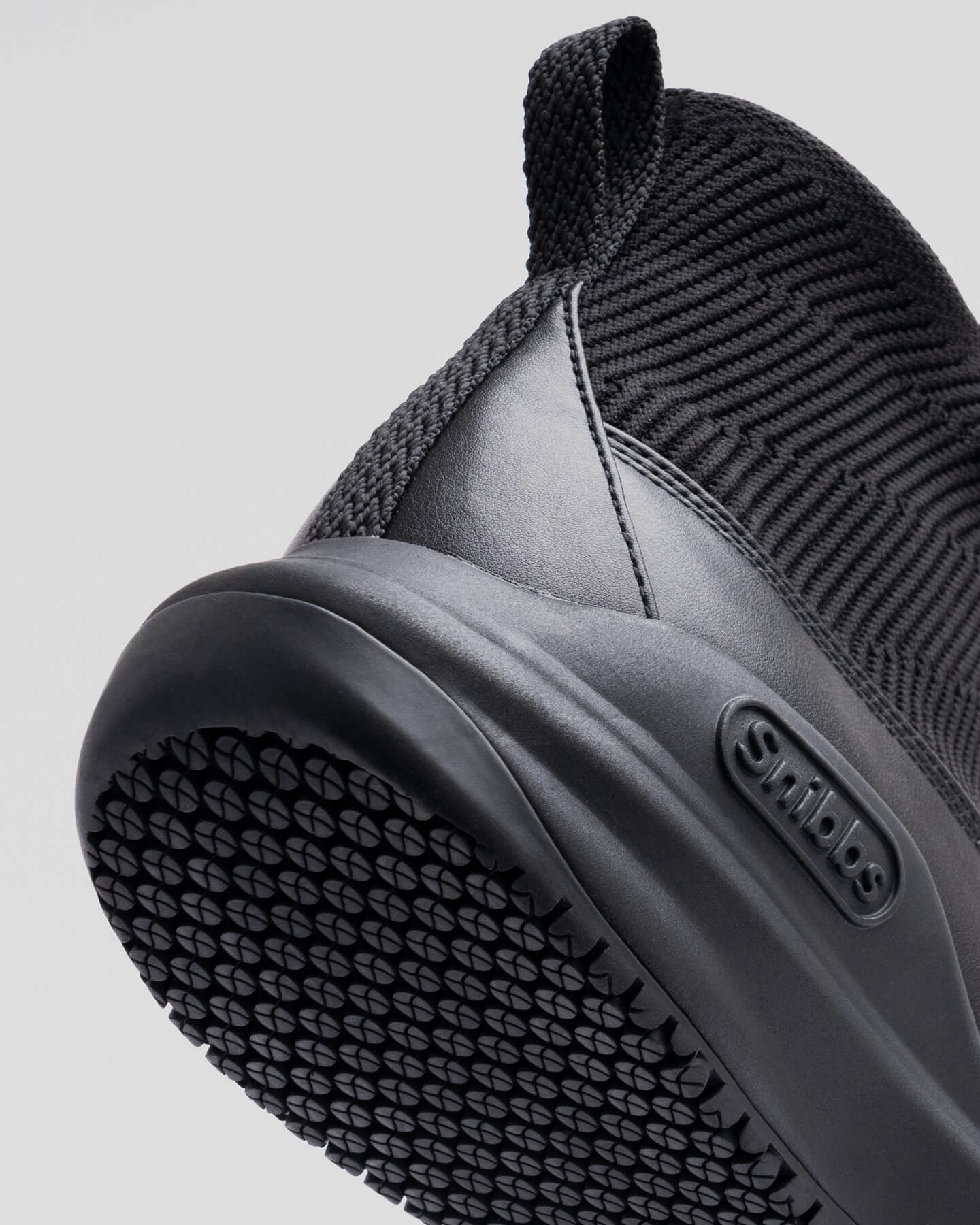 Close-up of Pro - Eclipse Black by Snibbs, featuring a premium knit upper, textured grip heel and sole, and side branding.