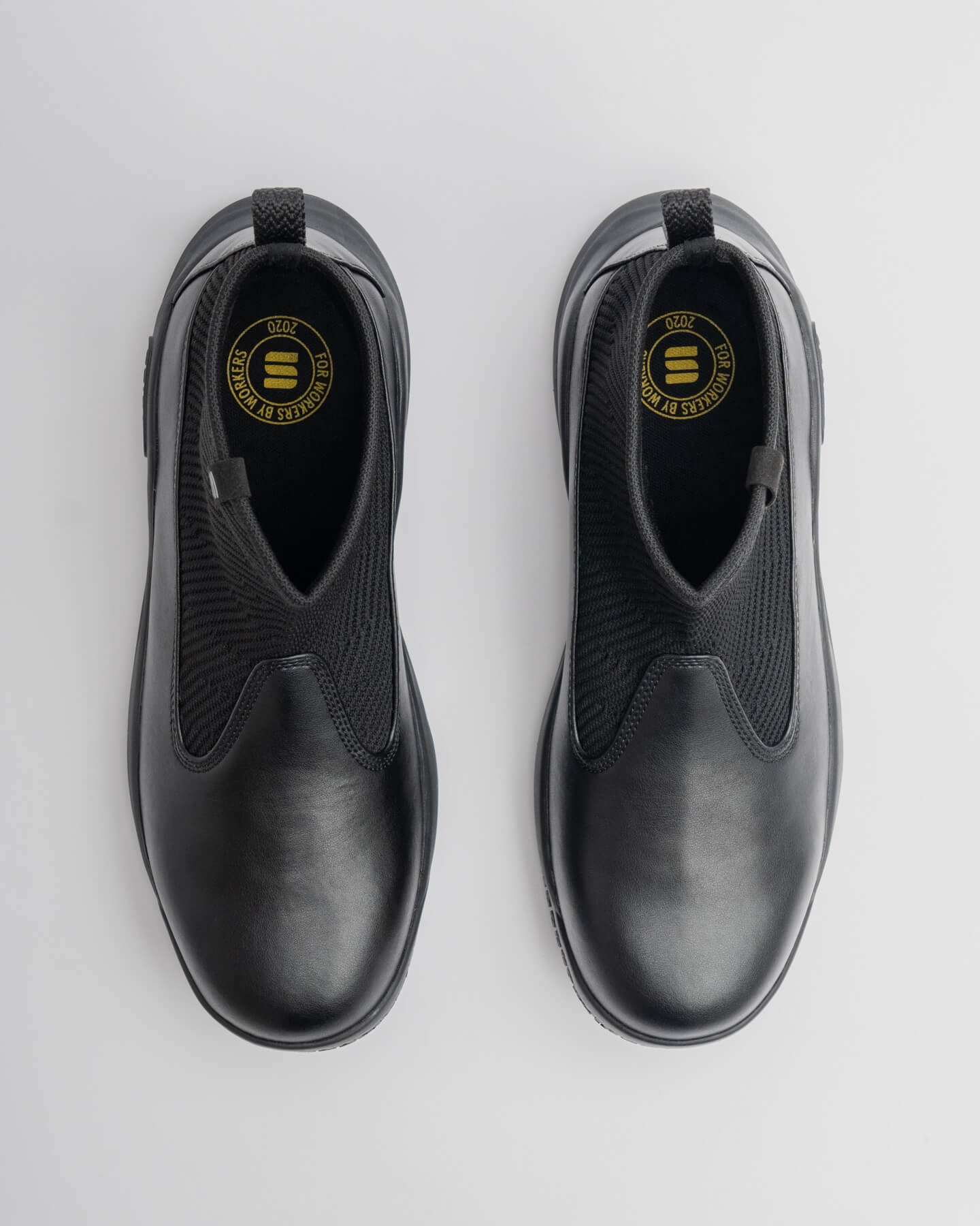 Snibbs Pro - Eclipse Black slip-ons feature a premium knit upper with leather accents, shown from above on a light gray background.