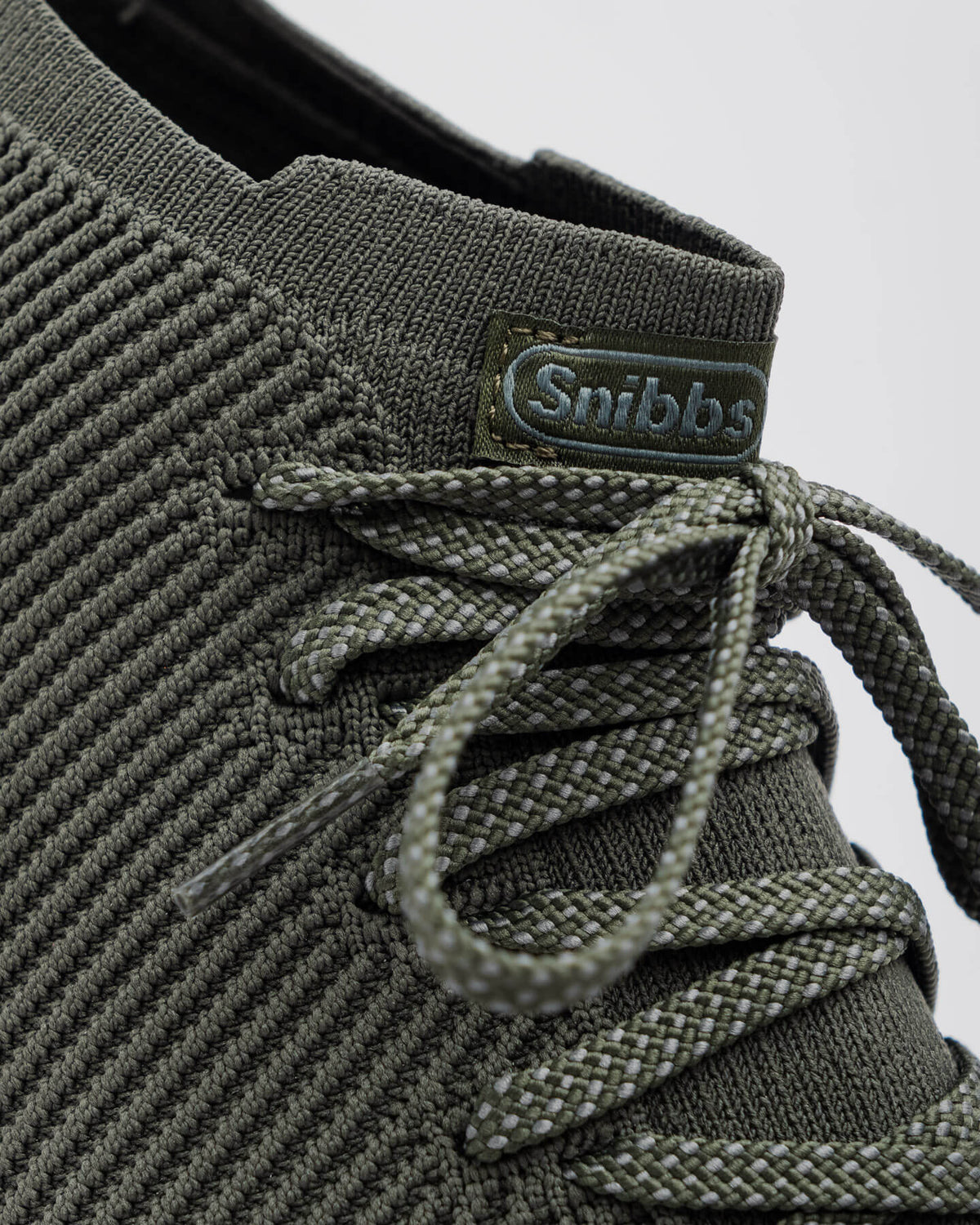 Close-up of the Snibbs ROVR Mid - Climbing Ivy sneaker with slip-resistant soles and a green "Snibbs" tag on the tongue.