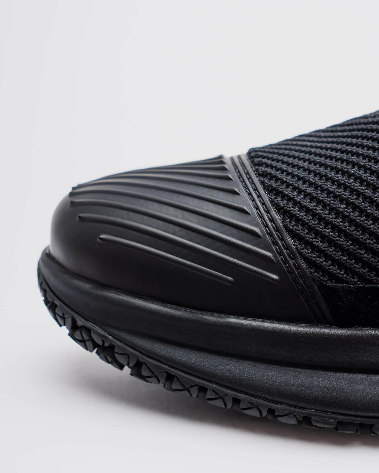Close-up of Snibbs ROVR Mid - Eclipse Black's ridged rubber toe, mesh, and slip-resistant sole on a white background.