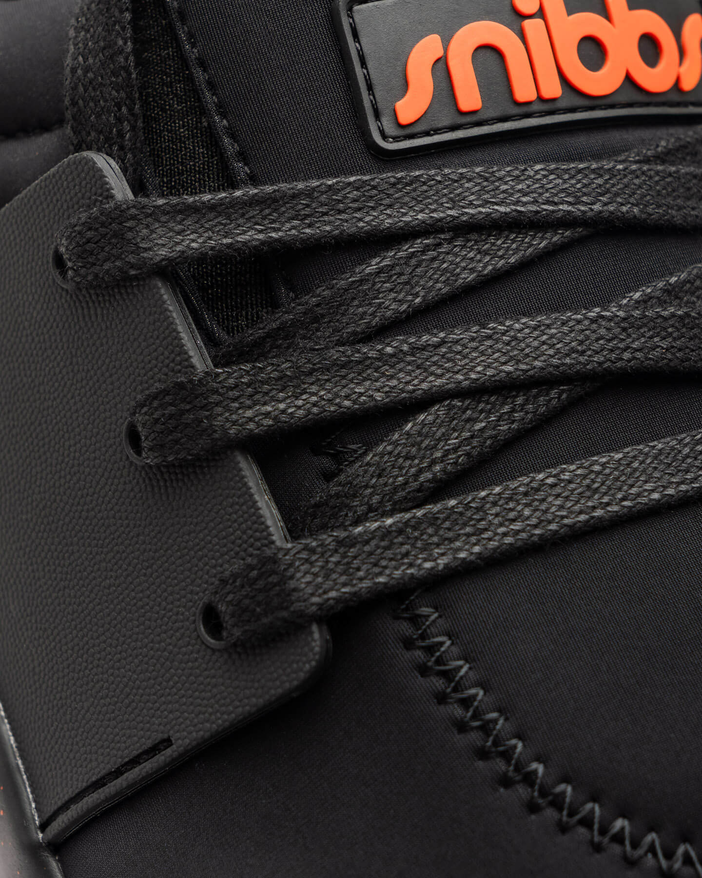 Close-up of the Snibbs Spacecloud 2.0 - Tangerine vegan sneaker with black laces and an orange "snibbs" logo on the tongue.
