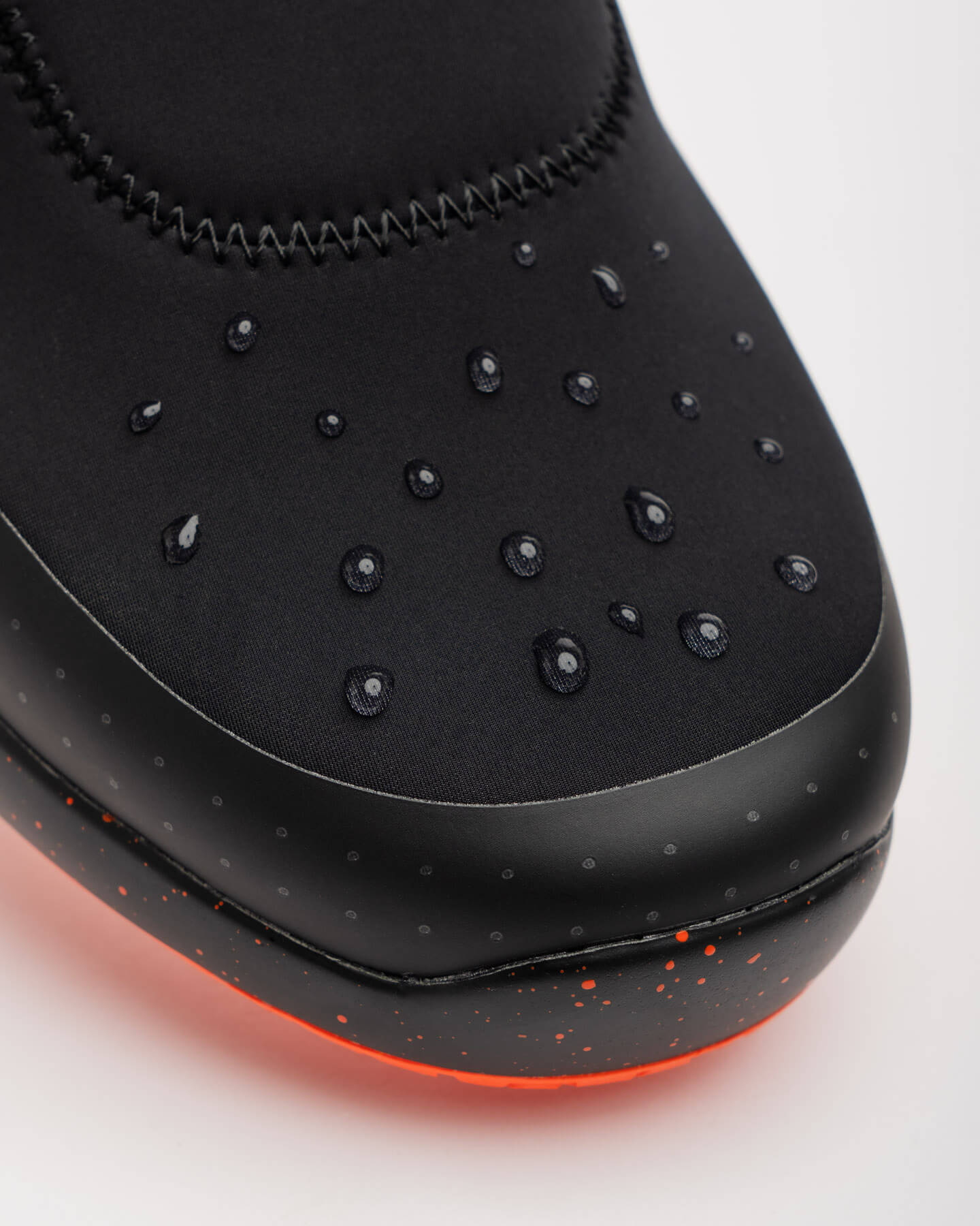 Close-up of Snibbs Spacecloud 2.0 - Tangerine vegan slip-resistant sneaker with water droplets on a white background.