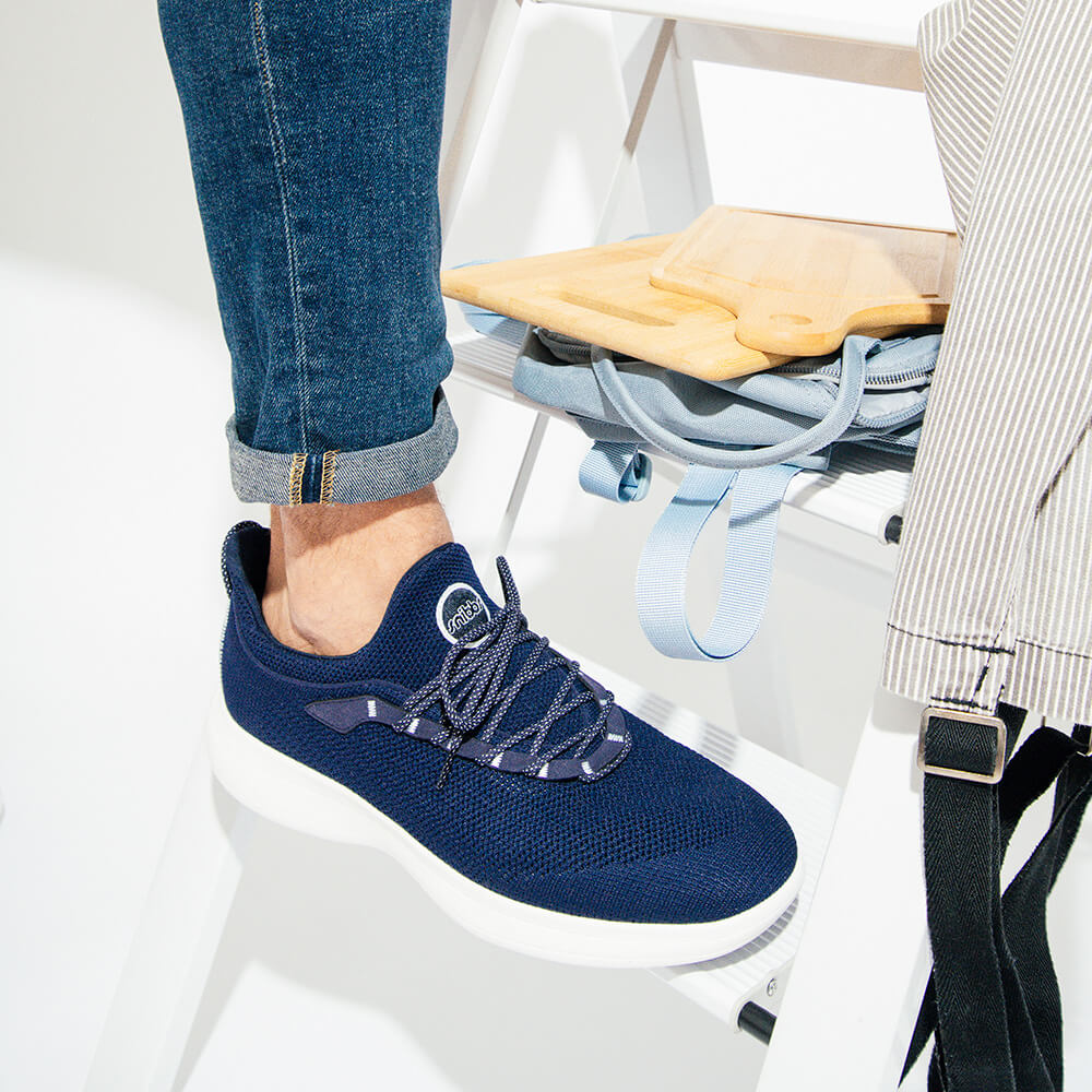 Someone in Snibbs Orbit - Maritime Blue sneakers and rolled jeans stands on a ladder with a cutting board and cloth nearby.