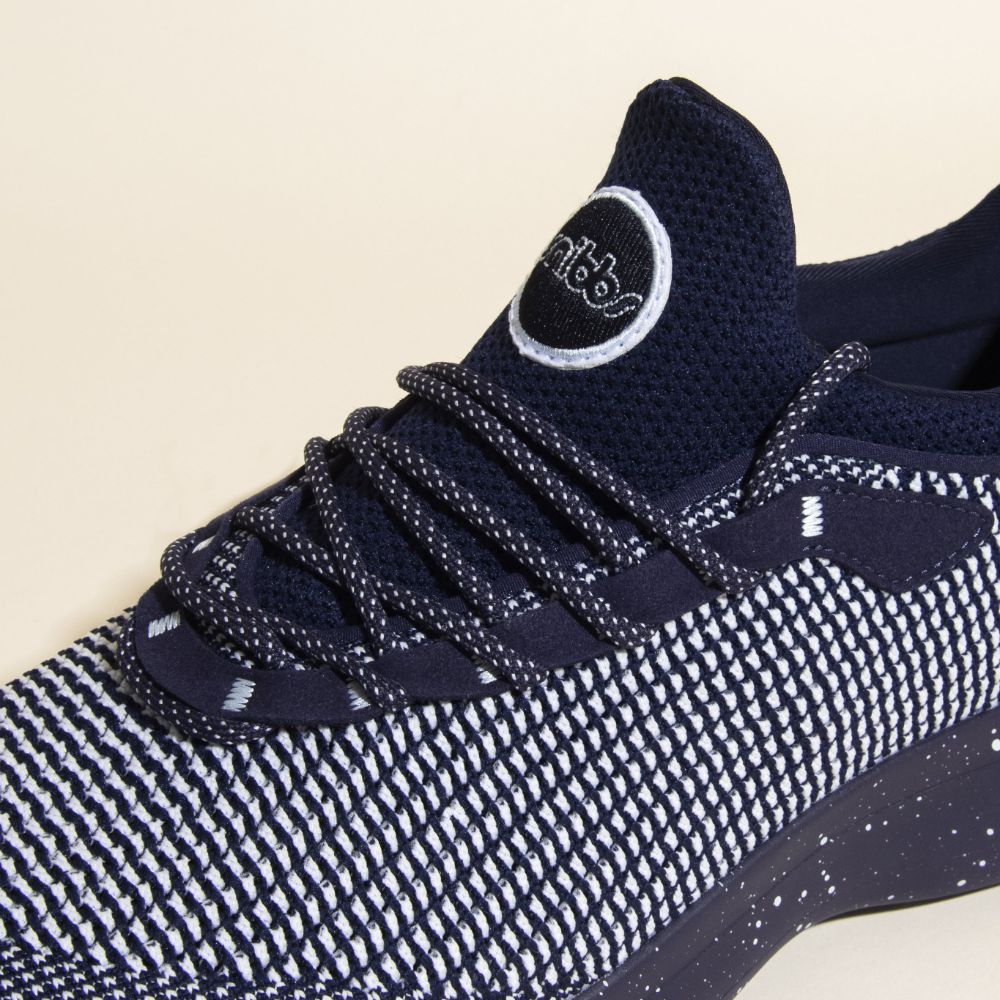 A close-up of Snibbs Orbit - Blueberry Jam sneaker featuring patterned laces, slip-resistant sole, and a circular logo on the tongue.