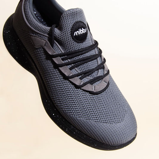 The Snibbs Orbit - Charcoal: a gray sneaker with black laces, slip-resistant lightweight sole, and a breathable knit upper.