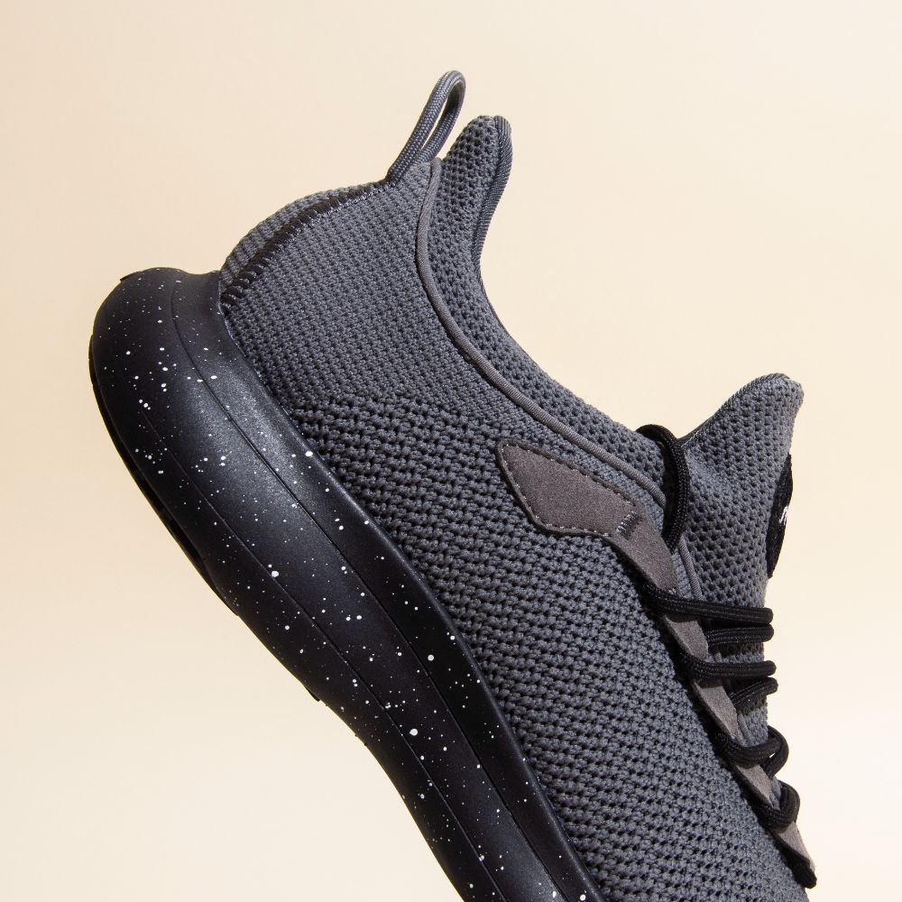Snibbs Orbit - Charcoal: Gray knit sneaker with black laces, breathable upper, and slip-resistant speckled black sole.
