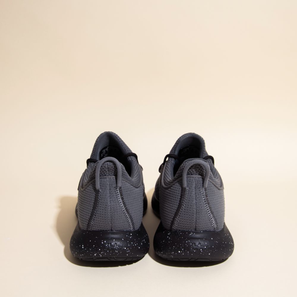 Snibbs Orbit - Charcoal athletic shoes with breathable knit uppers and black speckled soles shown from the back on a beige background.