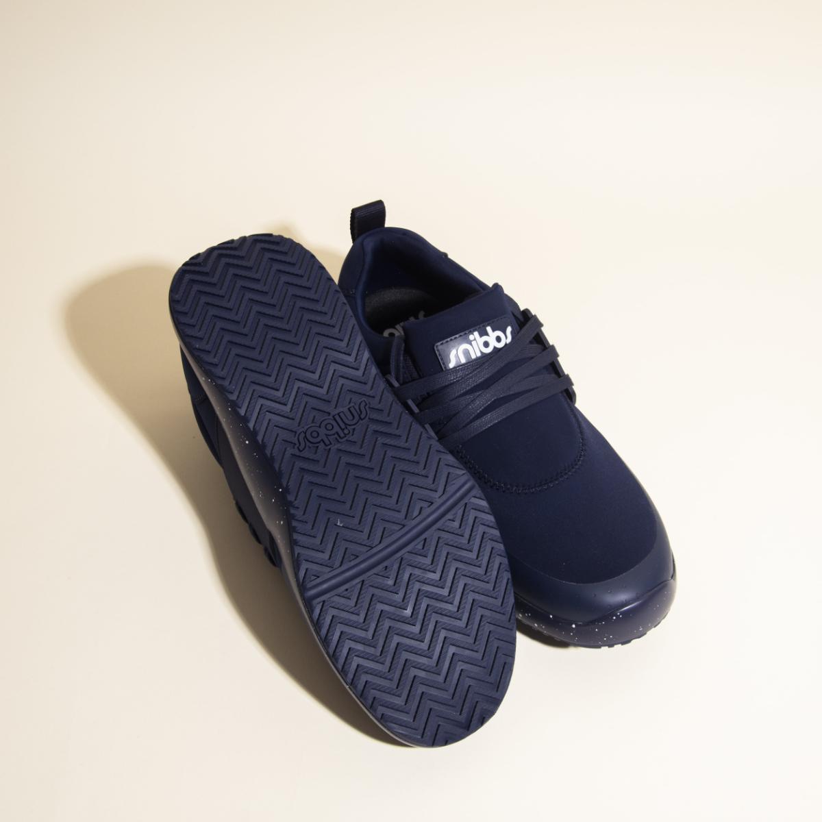 A pair of Snibbs Women's Spacecloud sneakers in Nebula Blue; one shoe stands upright while the other lies on its side, displaying a slip-resistant zigzag tread pattern on the sole.
