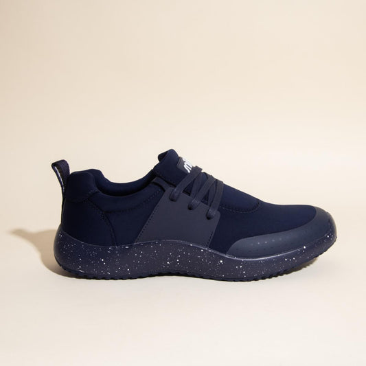 The Snibbs Women's Spacecloud - Nebula Blue is a navy blue athletic work sneaker featuring a speckled dark sole, slip-resistant tread, lace-up design, and a pull tab at the heel, displayed on a light beige background.